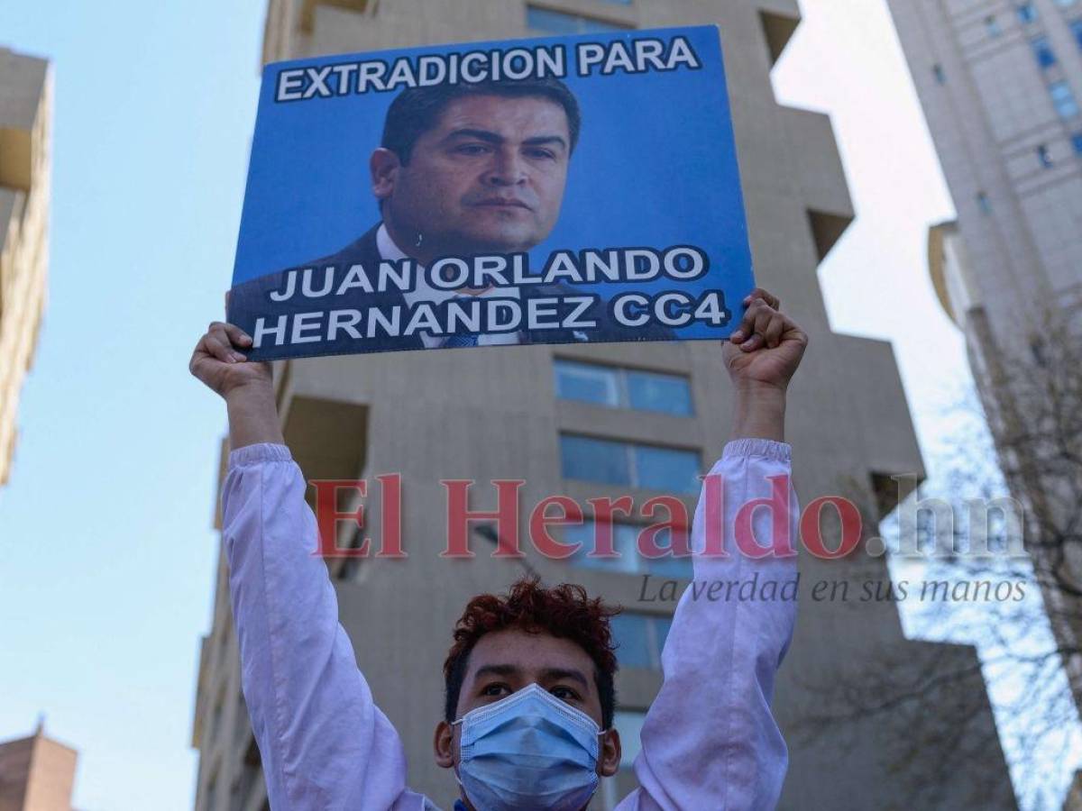 Un joven catracho levanta un cartel con foto de JOH por la extradición.