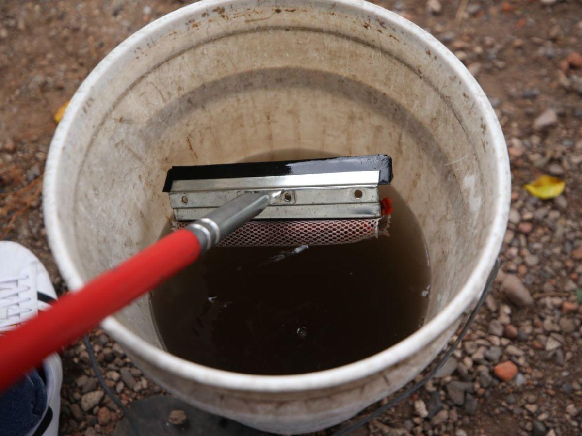 Un balde con agua regalada y la escobilla para limpiar los vidrios son las herramientas de muchos jóvenes en la capital.