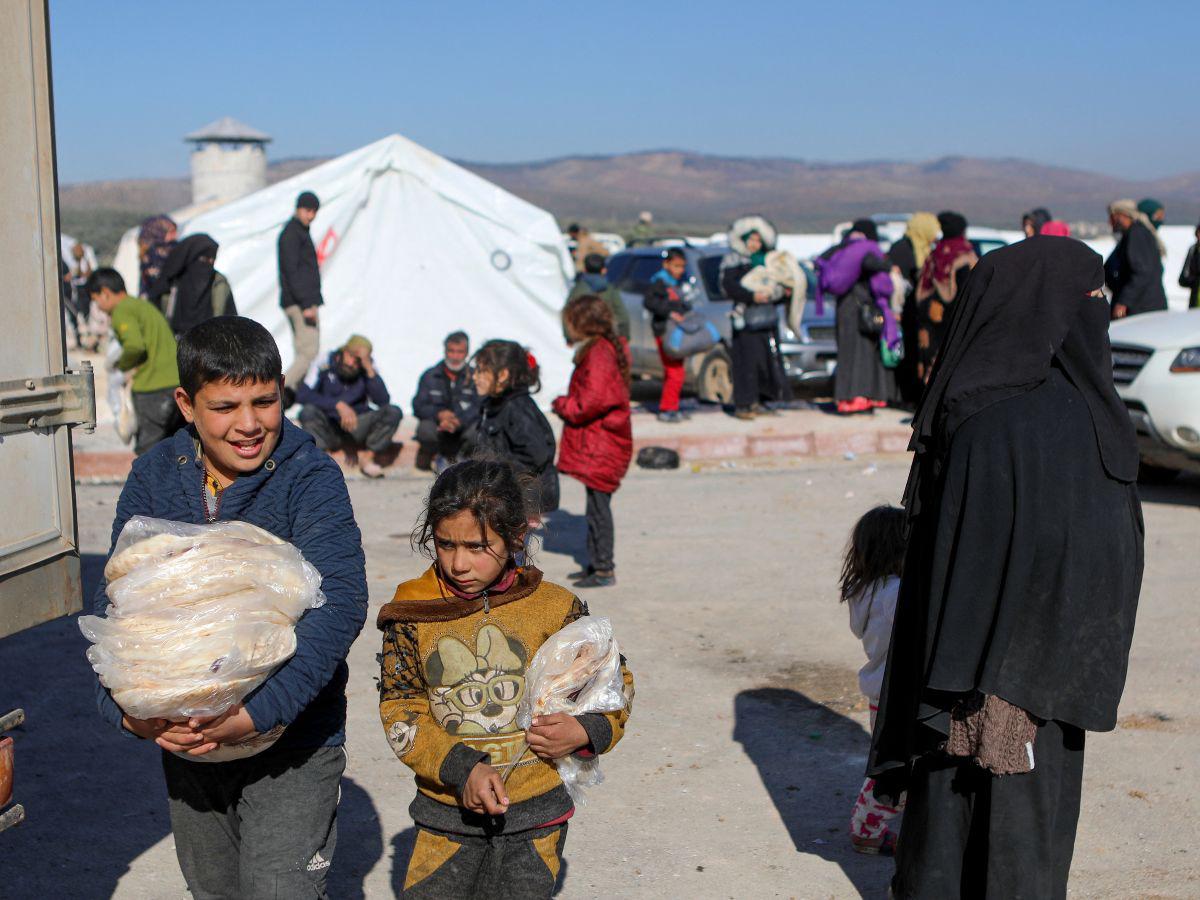 Niños sirios cargan pan en un refugio improvisado para personas que quedaron sin hogar, cerca de la ciudad de Jindayris, controlada por los rebeldes, el 9 de febrero de 2023, dos días después de que un terremoto mortal azotara Turquía y Siria.