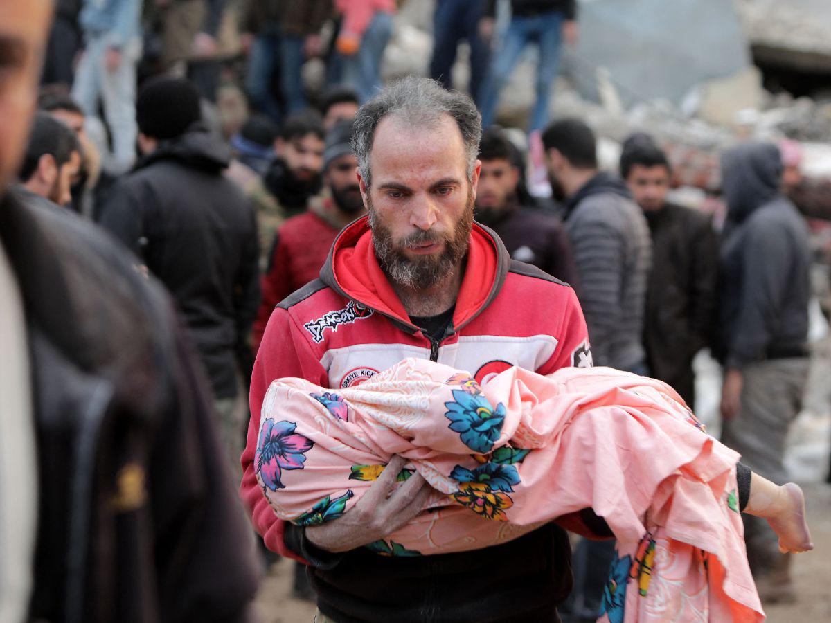 Un hombre sirio lleva el cuerpo de un niño el 7 de febrero de 2023 en la ciudad de Jindayris, en la parte rebelde de la provincia de Alepo, mientras continúan las operaciones de búsqueda y rescate después de un terremoto mortal.