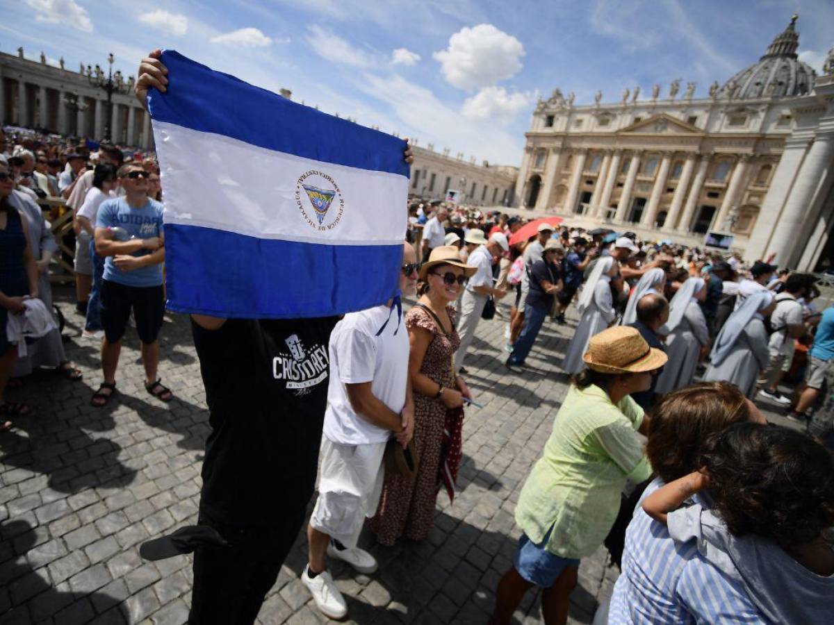 Un hombre sostiene la bandera nacional de Nicaragua en la plaza de San Pedro durante la oración semanal del Ángelus del Papa el 21 de agosto de 2022 en el Vaticano, pues también se ha denunciado persecución contra líderes religiosos.