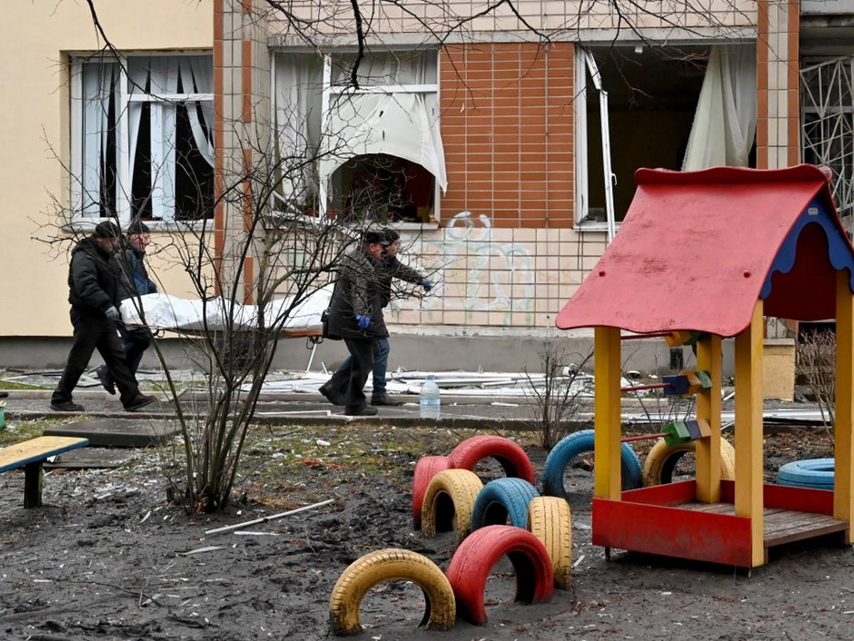 Cuatro hombres llevan una bolsa con un cuerpo en el sitio donde un helicóptero se estrelló cerca de un jardín de infantes, matando al menos a 14 personas, entre ellos un niño y al ministro de Interior.