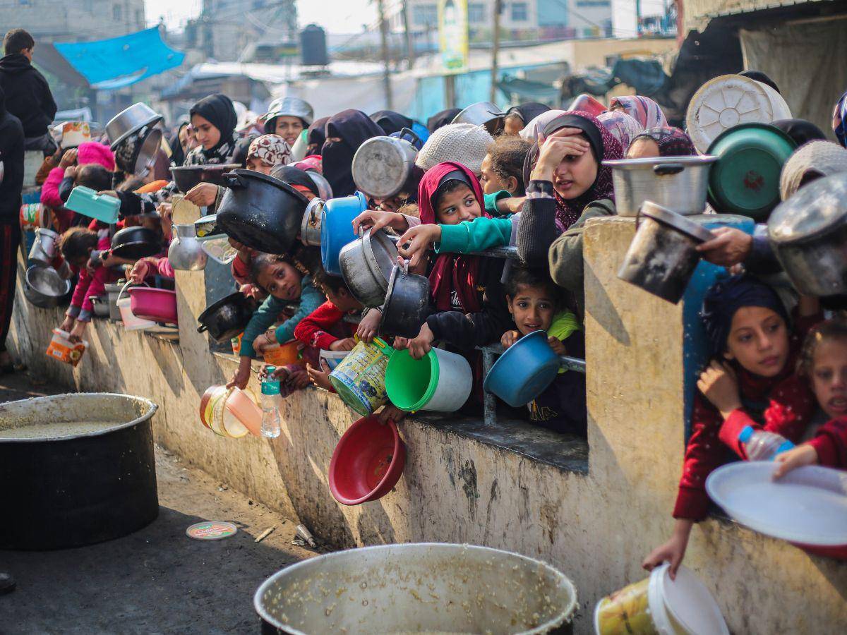 $!Palestinos se agolparon para una comida gratis en Rafah, en Gaza. La escasez de alimentos es tan extrema que cumple el primer criterio de una hambruna. (Ahmad Hasaballah/Getty Images)