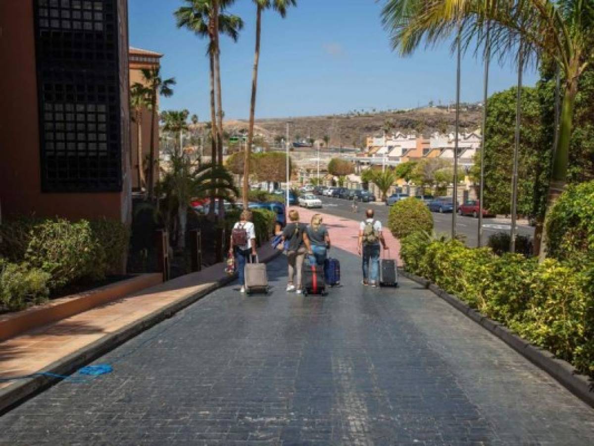 Several guests, on March 10, 2020, leave the H10 Costa Adeje Palace Hotel in La Caleta, where hundreds of people have been confined for a 14-day quarantine, after an Italian tourist was hospitalised with a suspected case of coronavirus. - The remaining guests at a hotel in Spain's Canary Islands on lockdown over the coronavirus were cleared today to leave the building after completing their 14-day quarantine period. Hotel workers and medical staff cheered and applauded in the early hours as a policeman cut a plastic ribbon that was blocking access to Tenerife's H10 Costa Adeje Palace, images broadcast on Spanish television showed. (Photo by DESIREE MARTIN / AFP)