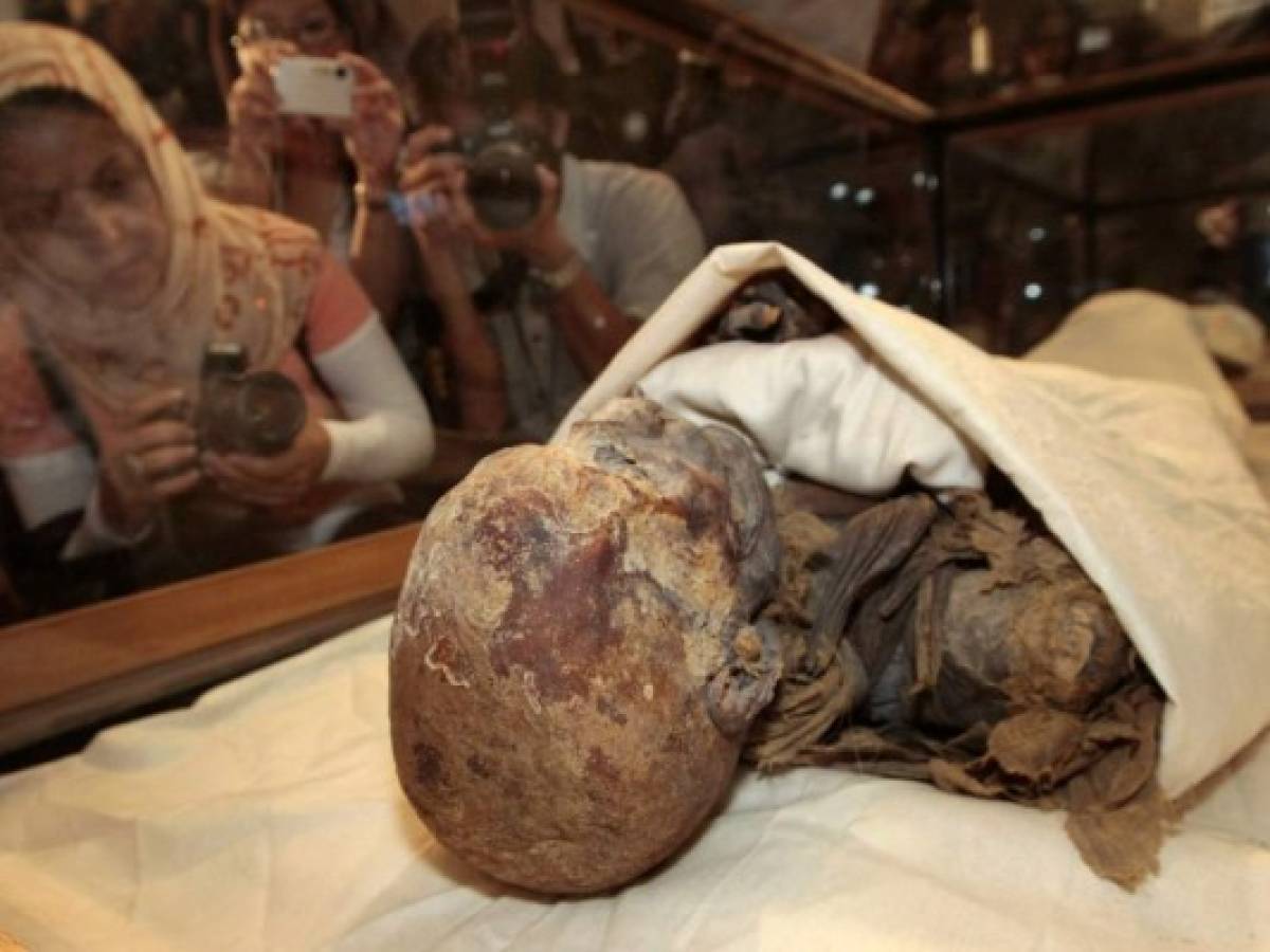 (FILES) In this file photo taken on June 27, 2007, people take pictures of the mummified remains of Queen Hatshepsut, ancient Egypt's most famous female pharaoh, displayed in a glass case after being unveiled at the Cairo Museum. - The mummies of 18 ancient Egyptian kings and four queens will be paraded through the streets of Cairo on April 3 evening, in a carnival procession dubbed the Pharaohs' Golden Parade, as they are moved from a long residency at the Egyptian Museum to be put on display at southern Cairo's National Museum of Egyptian Civilisation. (Photo by Cris BOURONCLE / AFP)