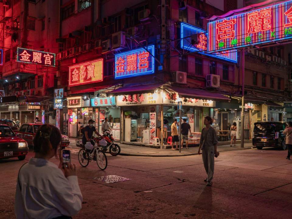 Posan bajo los rótulos de neón de centros nocturnos de karaoke en octubre en Hong Kong.