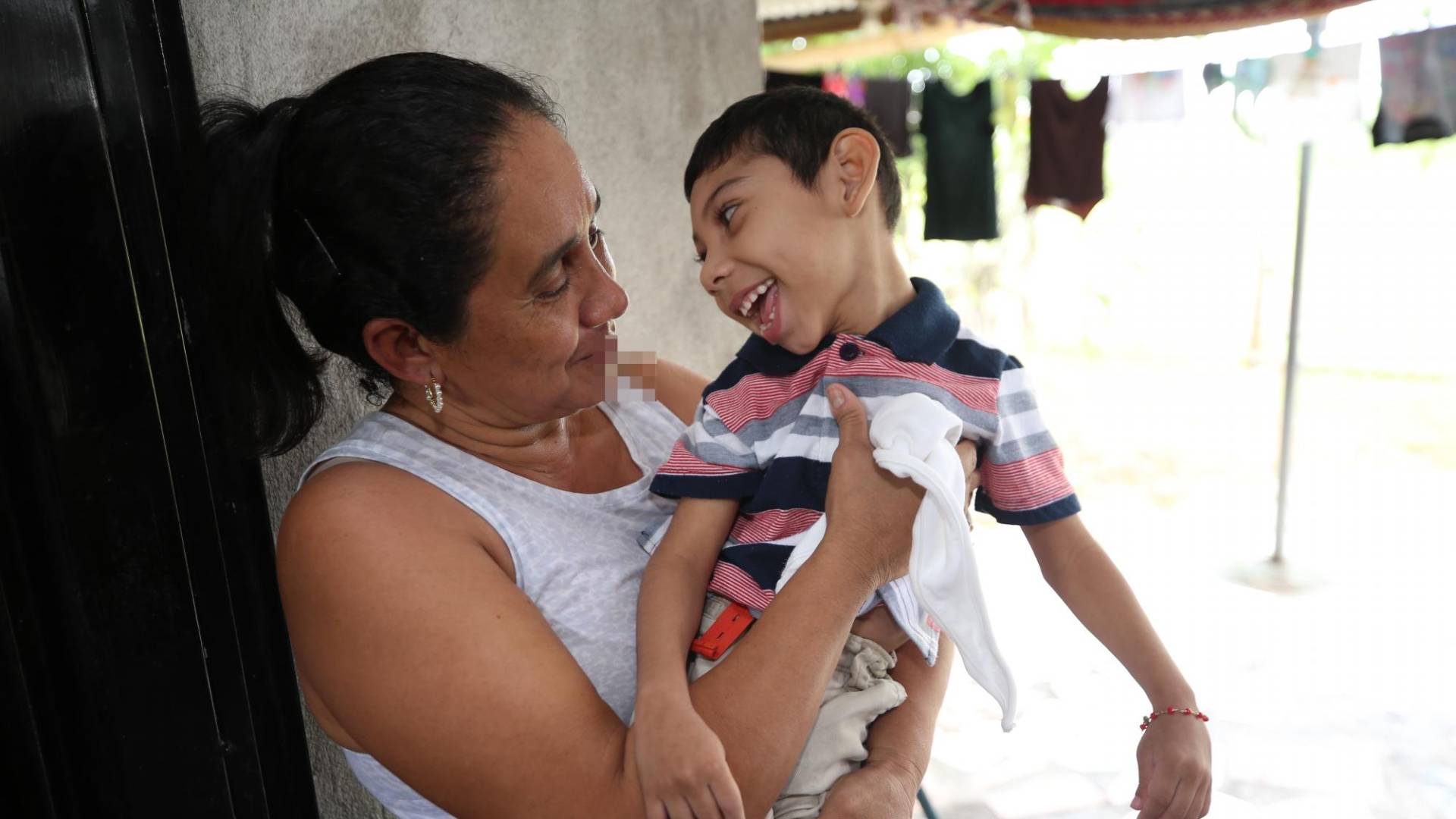 $!Ángel sonríe con su mamá, María, quien lo carga en el patio de su casa, ubicada en Ciudad Nueva, Choluteca.