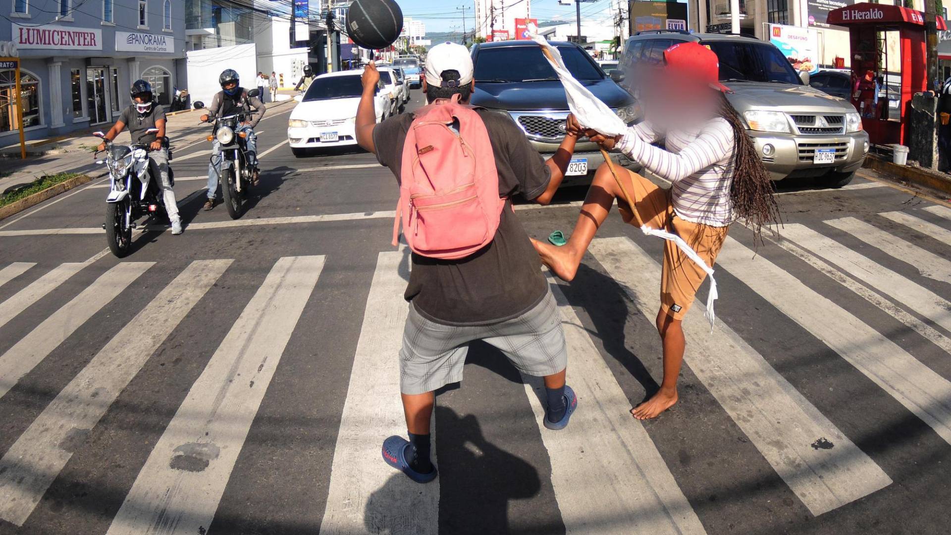 $!A pesar del potente sol, María camina sobre el pavimento para iniciar su espectáculo que le sirve para ganar un poco de dinero. El joven que la sostiene se presentó como su hermano.