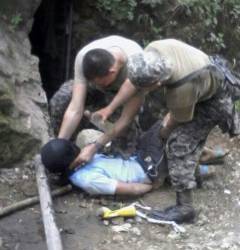 En la imagen se observa cómo dos uniformados sostienen a una de las víctimas, que mantienen con el rostro cubierto con una camiseta negra, para luego rociarle chorros de agua.