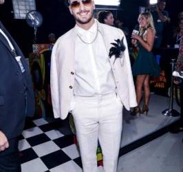 Maluma uno de los más elegantes de la noche con un look deportivo y su broche de plumas que lo hacen parecer de los 50.