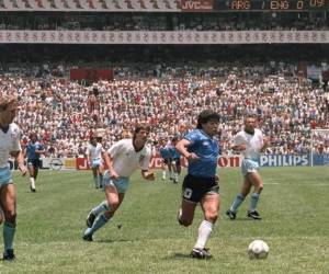 El delantero argentino Diego Armando Maradona pasa junto a los defensores ingleses Terry Butcher (izq.) Y Terry Fenwick (segundo izq.) En su camino para anotar su segundo gol durante el partido de cuartos de final de la Copa del Mundo entre Argentina e Inglaterra. .Argentina avanzó a semifinales con una victoria por 2-1. AFP PHOTO La leyenda del fútbol argentino Diego Maradona falleció el 25 de noviembre de 2020. Foto: Agencia AFP.