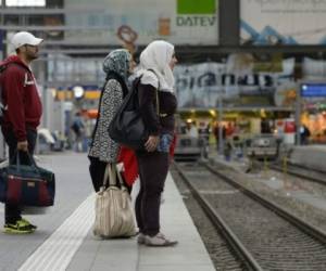 Migrantes esperando en la estación de tren. Foto: AFP