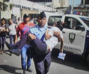 Momento en el que un agente policial llevaba en brazos a uno de los menores de edad heridos en el tiroteo de la colonia Sagastume de la capital de Honduras (Foto: Redes)