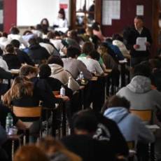 Estudiantes realizan un examen mientras su profesor los supervisa.