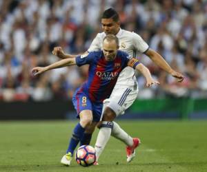 Barcelona's Andres Iniesta, left, challenges for the ball with RReal Madrid's Casemiro during a Spanish La Liga soccer match between Real Madrid and Barcelona, dubbed 'el clasico', at the Santiago Bernabeu stadium in Madrid, Spain, Sunday, April 23, 2017. (AP Photo/Francisco Seco)