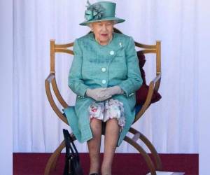 La reina asistió a la ceremonia vestida con un conjunto de color aguamarina, con el sombrero a juego, sonriente y observando a los guardias que estaban a más de dos metros de distancia entre sí. Foto: AFP