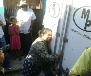 Una mujer se aferra al vehículo de la morgue forense que traslada el cuerpo de un pariente.