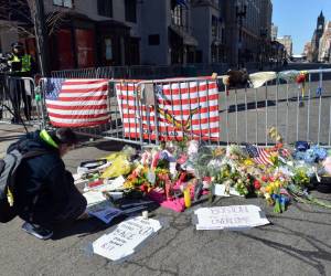 A kneels at a makeshift memorial a short distance from the finish line April 17, 2013 in Boston, Massachusetts, in the aftermath of two explosions that struck near the finish line of the Boston Marathon April 15. AFP PHOTO/Stan HONDA