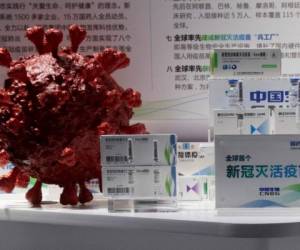 Muestras de una vacuna contra covid-19 producidas por la subsidiaria de Sinopharm, CNBG, se muestran cerca de un modelo 3D de coronavirus en Beijing, el 6 de septiembre de 2020.