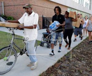 Varias personas que fueron afectadas por Florence y permanecen en albergues caminan a recibir comidas preparadas, agua y lonas en un centro de distribución en Wilmington, Carolina del Norte. Foto AP
