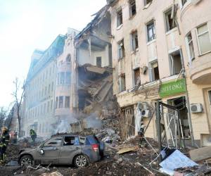 Los bomberos trabajan para limpiar los escombros y extinguir un incendio en un edificio gravemente dañado después de que un cohete ruso explotara en las afueras de la segunda ciudad de Ucrania, Kharkiv, el 14 de marzo de 2022, en medio de la actual invasión rusa de Ucrania. - El bombardeo mató a 2 civiles y dejó un herido, según funcionarios locales.
