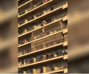El hombre que estaba varios apartamentos más allá comienza a avanzar por fuera del balcón para lograr llegar más rápido hasta el pequeño. (Foto: Captura de vídeo)