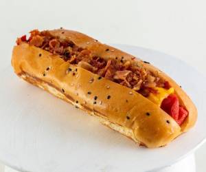 El hot dog con tocino y cebolla caramelizada estilo estadio, una salchicha sobre un pan suave que no necesita presentación.