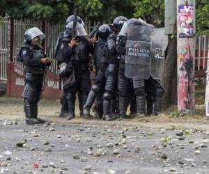 Un manifestante enmascarado ondea una bandera de Nicaragua frente a una barricada en llamas mientras manifestantes se enfrentan con la policía en Monimbo, Masaya, Nicaragua, el sábado 12 de mayo de 2018. (AP Foto/Alfredo Zuniga)