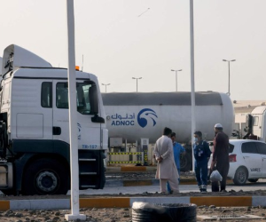 Los hombres se paran frente a una instalación de almacenamiento del gigante petrolero ADNOC en la capital de los Emiratos Árabes Unidos, Abu Dhabi, el 17 de enero de 2022. Foto: AFP