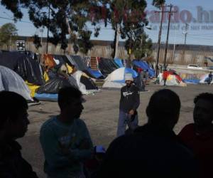 En esta imagen de archivo del 7 de diciembre de 2018, varios hombres comentan rumores de otros migrantes que entraron con éxito a Estados Unidos de forma clandestina, en un campamento ante el recinto deportivo cerrado Benito Juárez, en Tijuana, México. (AP Foto/Rebecca Blackwell, File)