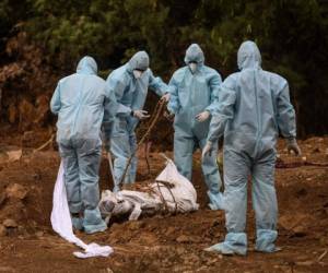 Los familiares que usan equipo de protección preparan el entierro del cadáver de una víctima que murió del coronavirus COVID-19 en un cementerio en Nueva Delhi el 10 de mayo de 2020. Foto: Agencia AFP.