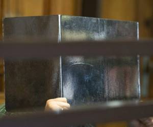 El acusado en un supuesto caso de canibalismo se cubre la cara con un cartón en la primera sesión de su juicio en Berlín. Foto: AP