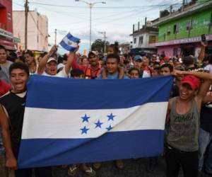 A migrant -alongside other Central Americans taking part in a caravan called 'Migrant Viacrucis' towards the United States- flutters a Guatemalan national flag during a march to protest against US President Donald Trump's policies in Matias Romero, Oaxaca State, Mexico, on April 3, 2018. The hundreds of Central Americans in the 'Way of the Cross' migrant caravan have infuriated Trump, but they are not moving very fast -- if at all -- and remain far from the US border. As Trump vowed Tuesday to send troops to secure the southern US border, the caravan was camped out for the third straight day in the town of Matias Romero, in southern Mexico, more than 3,000 kilometers (1,800 miles) from the United States. / AFP PHOTO / VICTORIA RAZO