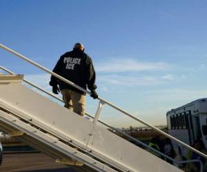 Un agente observa mientras inmigrantes que ingresaron ilegalmente a Estados Unidos son deportados en un vuelo a El Salvador por parte del Servicio de Control de Inmigración y Aduanas en Houston. Foto: AP.