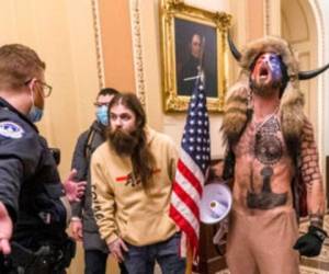A la derecha, con la cara pintada, un casco con cuernos y sin camisa, se ve a Jacob Chansley durante el asalto al Capitolio en Washington. Foto: AP
