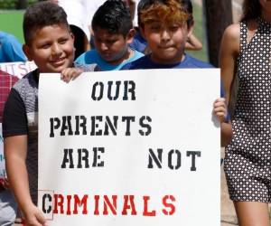 En esta fotografía de archivo del 11 de agosto de 2019, menores hijos de padres latinos sostienen un cartel en apoyo a sus progenitores y de las personas arrestadas durante una redada contra los inmigrantes no autorizados en una planta procesadora de carne, en Catón, Missouri. El letrero dice “Nuestros padres no son delincuentes”. Fotos: Agencia AP.