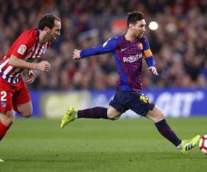 El delantero del Barcelona Lionel Messi (derecha) se desmarca del zaguero Diego Godín del Atlético de Madrid en un partido de la Liga española en el estadio Camp Nou. (Foto: AP)