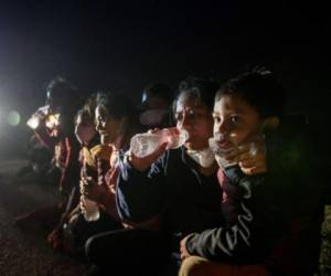 Varios migrantes, principalmente de Honduras y Nicaragua, hacen fila sentados después de entregarse al cruzar la frontera entre Estados Unidos y México. Foto: AP