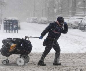 Un hombre intenta caminar con el coche de su hijo entre las fuertes rachas de viento. Foto AFP