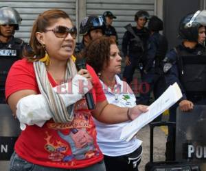Un periodista con un vendaje falso lee una declaración frente a los policías durante una protesta frente al Instituto Nacional Penitenciario de Tegucigalpa.