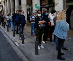 Decenas de personas haciendo cola para entrar a una carnicería en Atenas el 17 de abril del 2020. El uso de tapabocas por el coronavirus elimina una cantidad de gestos faciales que facilitan las comunicaciones entre las personas.