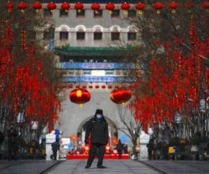 Un guardia de seguridad con mascarilla camina por la calle Quanmen, normalmente popular entre los turistas pero que aparece casi vacía, en Beijing. Foto: AP.