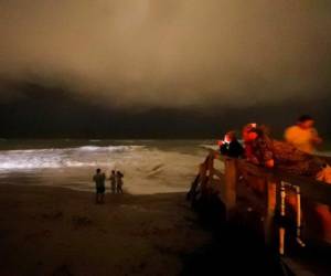 Varias personas caminan por el malecón mientras las bandas exteriores del huracán Dorian llegan a Vero Beach, Florida, la noche del lunes 2 de septiembre de 2019. Foto: Agencia AP.