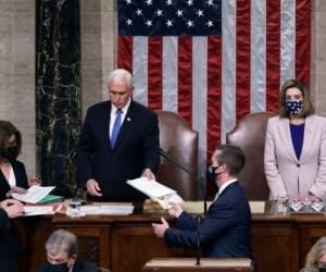 El vicepresidente Mike Pence entrega la certificación de West Virginia al personal como presidenta de la Cámara de Representantes, Nancy Pelosi, demócrata de California, escuche durante una sesión conjunta del Congreso después de trabajar toda la noche, en el Capitolio el 7 de enero , 2021 en Washington, DC. Foto: AFP