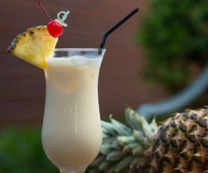 La piña colada, un icónico cóctel, asociado con playas de arena blanca y aguas cristalinas, símbolo caribeño.