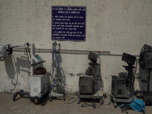 Las instrucciones para pacientes con COVID-19, en un cartel junto a equipos dañados en un letal incendio en un hospital en Bharuch, en el oeste de India, el 1 de mayo de 2021. (AP Foto/Viral Rana).