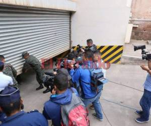 Autoridades militares cierran la cortina del sótano del edificio del Ministerio Público, al momento que forenses ingresaron los cuerpos a la morgue capitalina. Foto: Estalín Irías / El Heraldo.