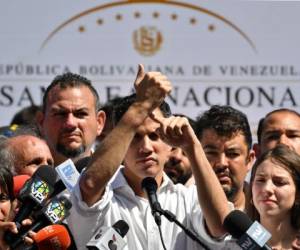 El presidente de la Asamblea Nacional de Venezuela, Juan Guaido, apunta a su muñeca mientras habla ante una multitud de partidarios de la oposición durante una reunión abierta en Vargas, Venezuela, el 13 de enero de 2019. Foto AFP