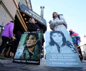 Brenda Jenkyns, a la izquierda, y Catherine Van Tighem, quienes condujeron desde Calgary, Canadá, se paran con pancartas afuera del cine donde se estrenó el documental sobre Michael Jackson 'Leaving Neverland' en el Festival de Cine de Sundance, el viernes 25 de enero del 2019 en Park City, Utah.