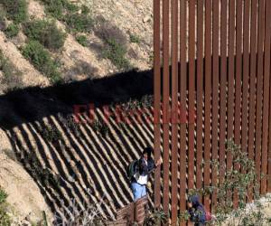 Los migrantes centroamericanos cruzan la valla fronteriza de Estados Unidos y México desde Tijuana, estado de Baja California, México. Agencia AFP.